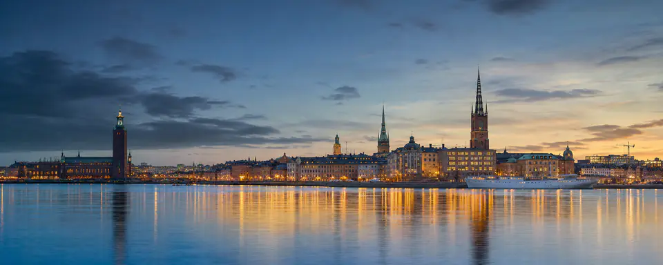 Illustrerat panorama över centrala Stockholms silhuett vid vattnet i skymningsljus